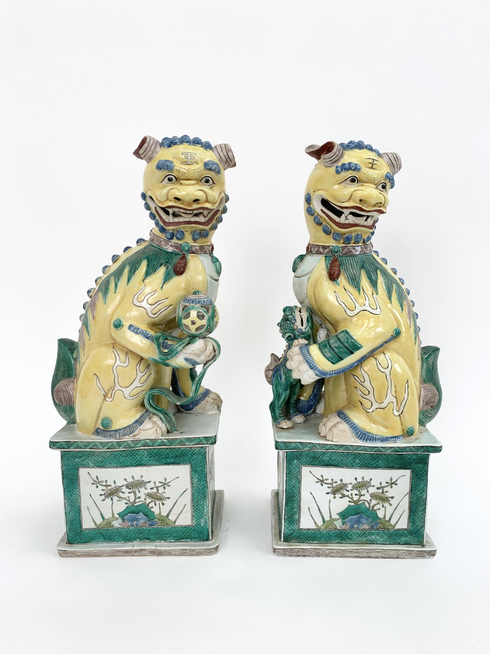 PAIR OF CHINESE FAMILLE JAUNE ET VERTE FOO DOGS: Large size. On plinths marked on bottom. Dimensions: H 18" x W 9" x D 6.5" Condition: Light wear consistent with age.