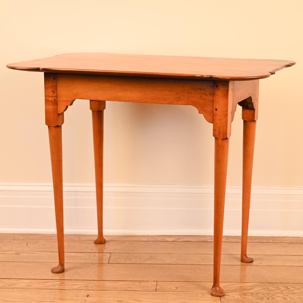 ELDRED WHEELER MAPLE PORRINGER TOP TEA TABLE: Shaped top and spade legs. In Queen Anne style. Marked underneath. Dimensions: H 27" x W 32.75" x D 22" Condition: A few very light surface marks.