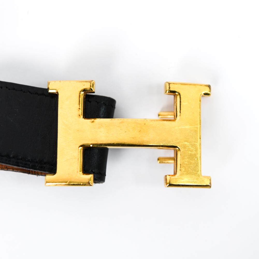 HERMÈS H BELT BUCKLE: Rectangular brass Hermes "H" buckle, early with double hook closure and reversible Hermes stitched leather belt. Dimensions: Buckle: H 1.5" x W 2.25", Belt: L 39" Condition: Scratching and denting to