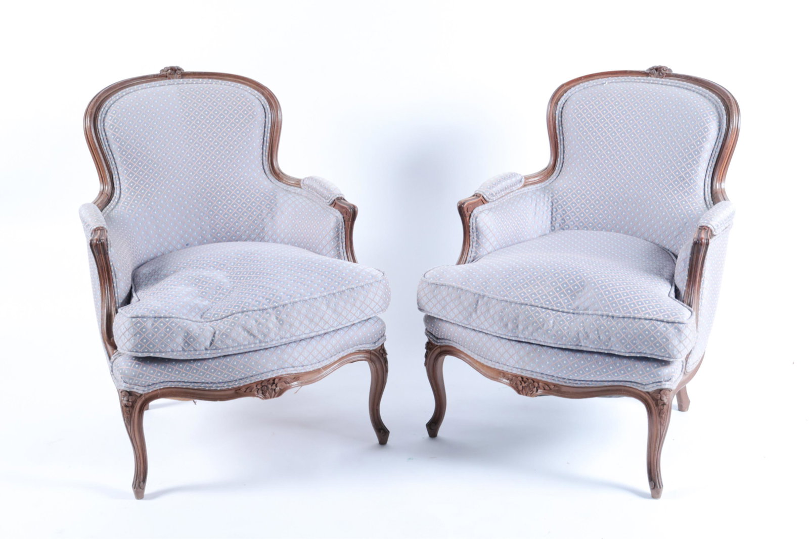 PAIR OF FRENCH STYLE BERGERE CHAIRS: In blue upholstery. Dimensions: H 33" x W 34" x D 24" x SH 18" Condition: Few small spots to upholstery. Some rubbing and nicks to wood. Some areas of piping loose.
