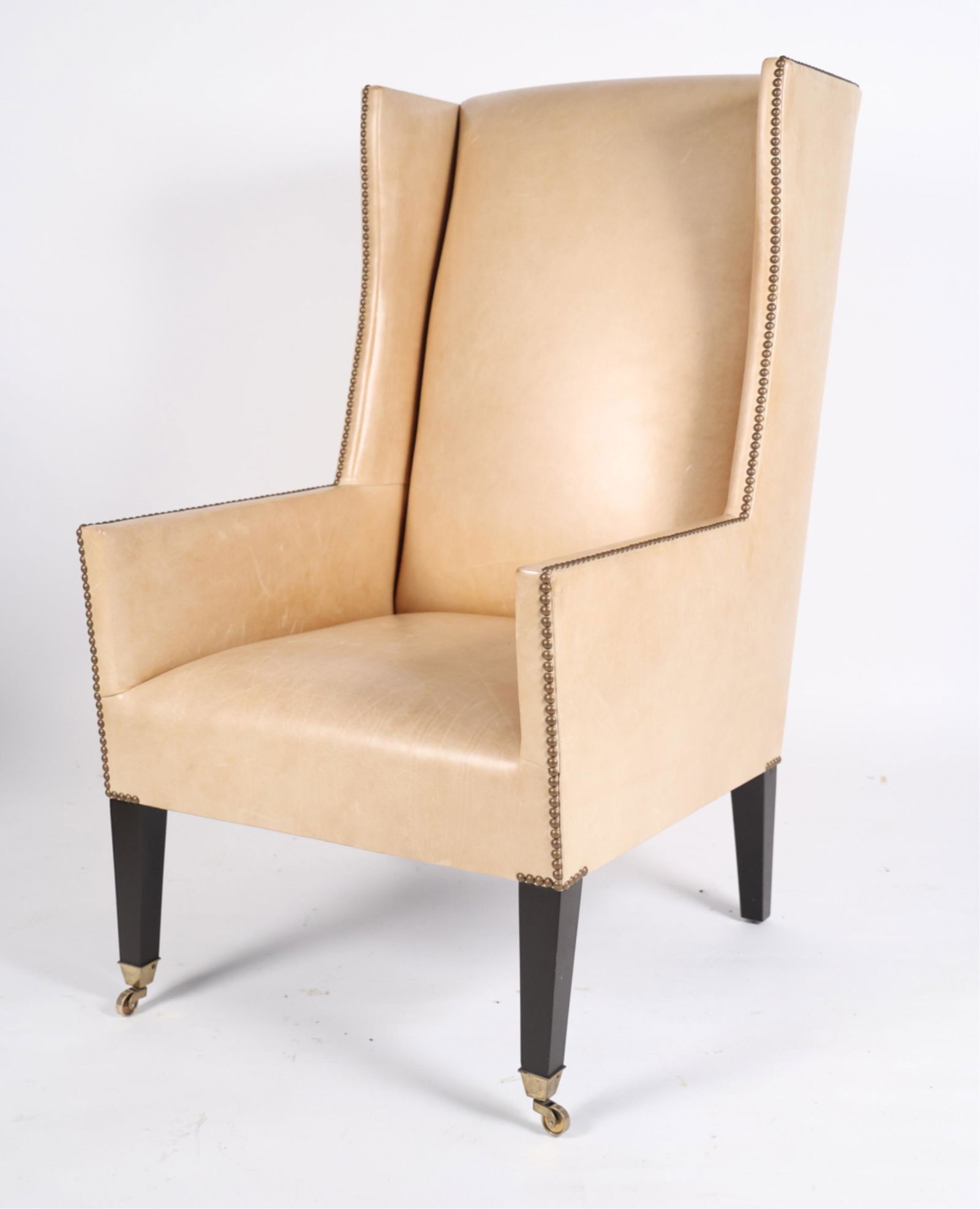 LEATHER WINGBACK CHAIR: Tacked leather upholstery. On casters. No labels. Dimensions: H 46" x W 26" x D 33" x SH 19" Condition: Some scuffs to leather. Some marks to legs.