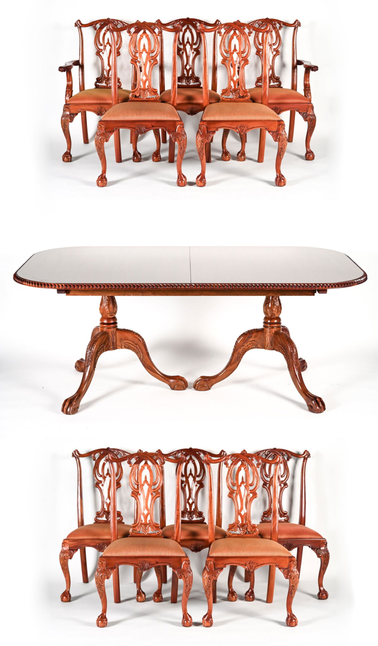 CARVED MAHOGANY DINING TABLE AND CHAIRS: Carved wood dining table with ball and claw feet. Comes with 2 leaves and table pads. 10 dining chairs with 2 armchairs. Chairs with ornate carved wood with ball and claw feet and fabric upholstered c