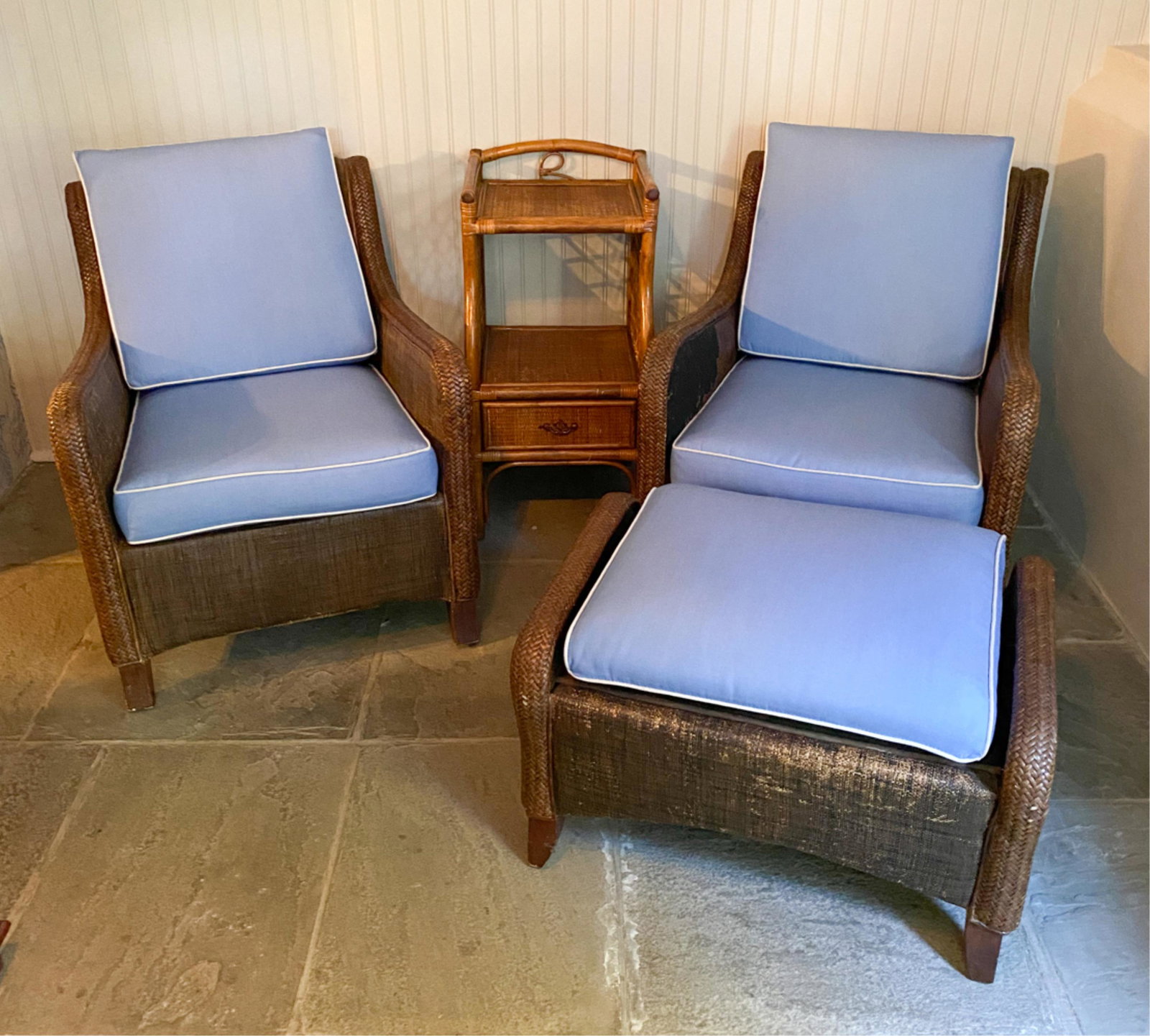 WOVEN RATTAN PATIO FURNITURE SUITE: Including two lounge chairs, ottoman, and side table. Dimensions: (Lounge chair) H 31.25" x W 26" x D 31" SH 17" Condition: Some breaks and rips. Surface and finish wear throughout. One chair with lar