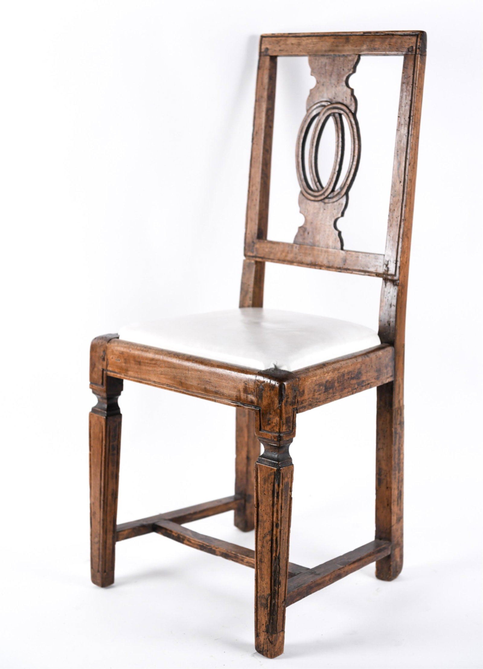 ANTIQUE WOODEN SIDE CHAIR: 19th C. or earlier. wooden pegs, Carved wood back with leather upholstery. Dimensions: H 36" x W 16.5" x D 15" SH 18" Condition: Dents and scratches throughout. Chair legs slightly uneven. Seat is not