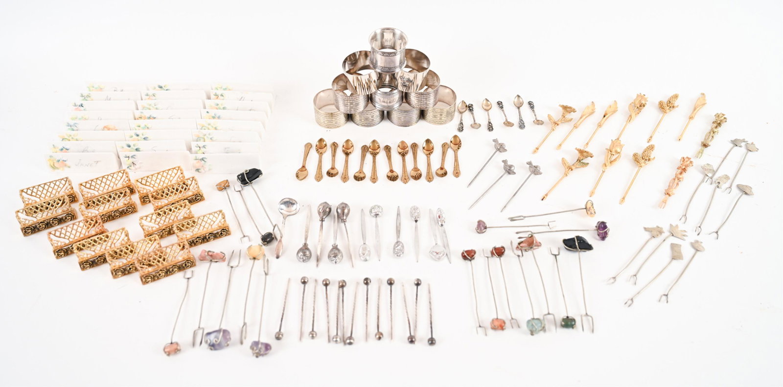 GROUPING INCL. NAPKIN RINGS, PLACE CARD HOLDERS: Including place card holders, napkin rings, charcuterie forks, salt spoons, etc. Including some marked sterling. Dimensions: (Napkin ring) H 1.25" x Dia. 1.75" Condition: Some tarnish, signs of use. F