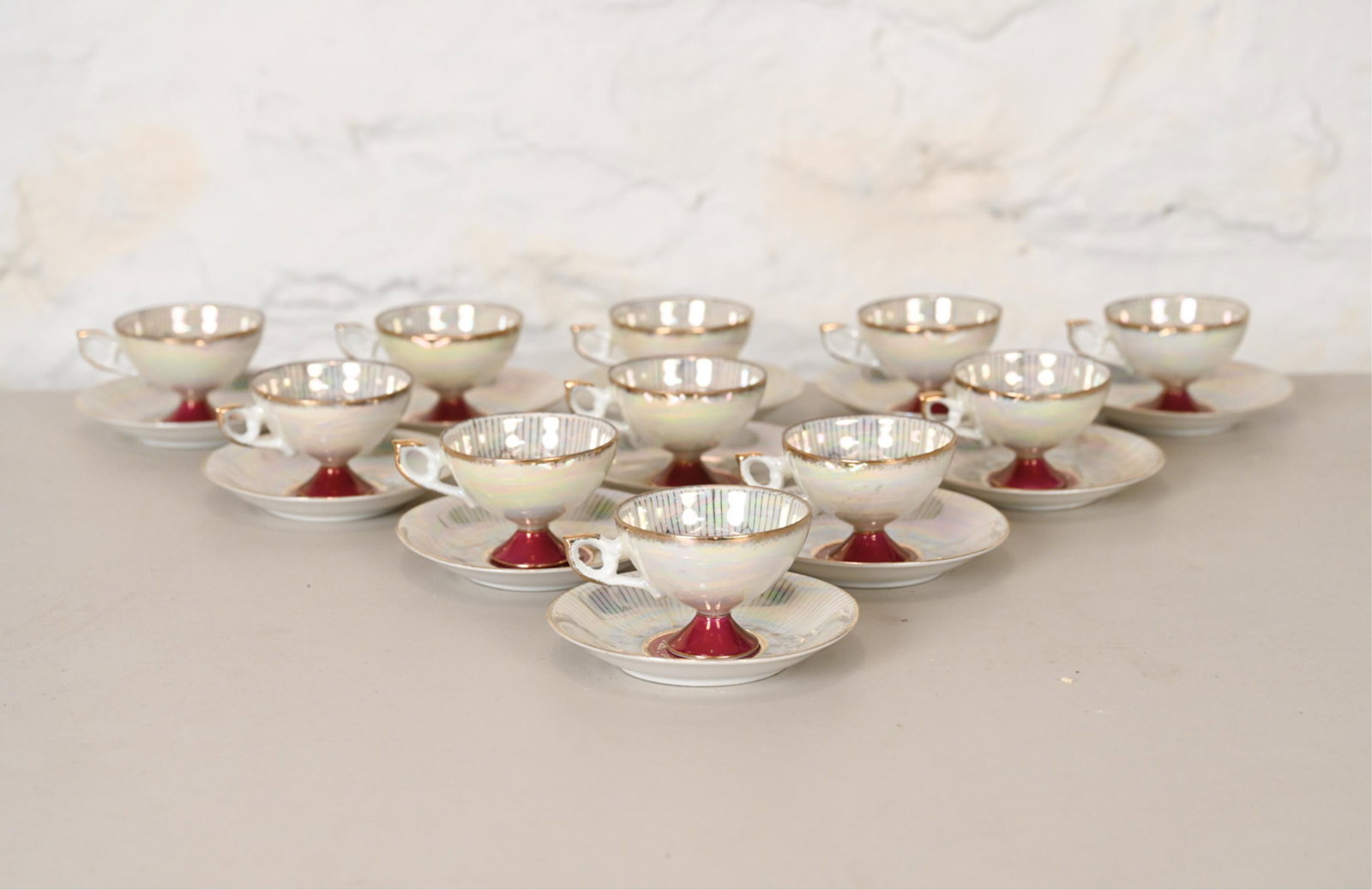 STERLING CHINA PORCELAIN CUP AND SAUCER GROUPING: Including (12) saucers and (11) tea cups. With gold trim and an iridescent glaze. Dimensions: (Tea cup) H 2.25" x Dia. 4" (Saucer) Dia. 5" Condition: Minor losses to the gold.