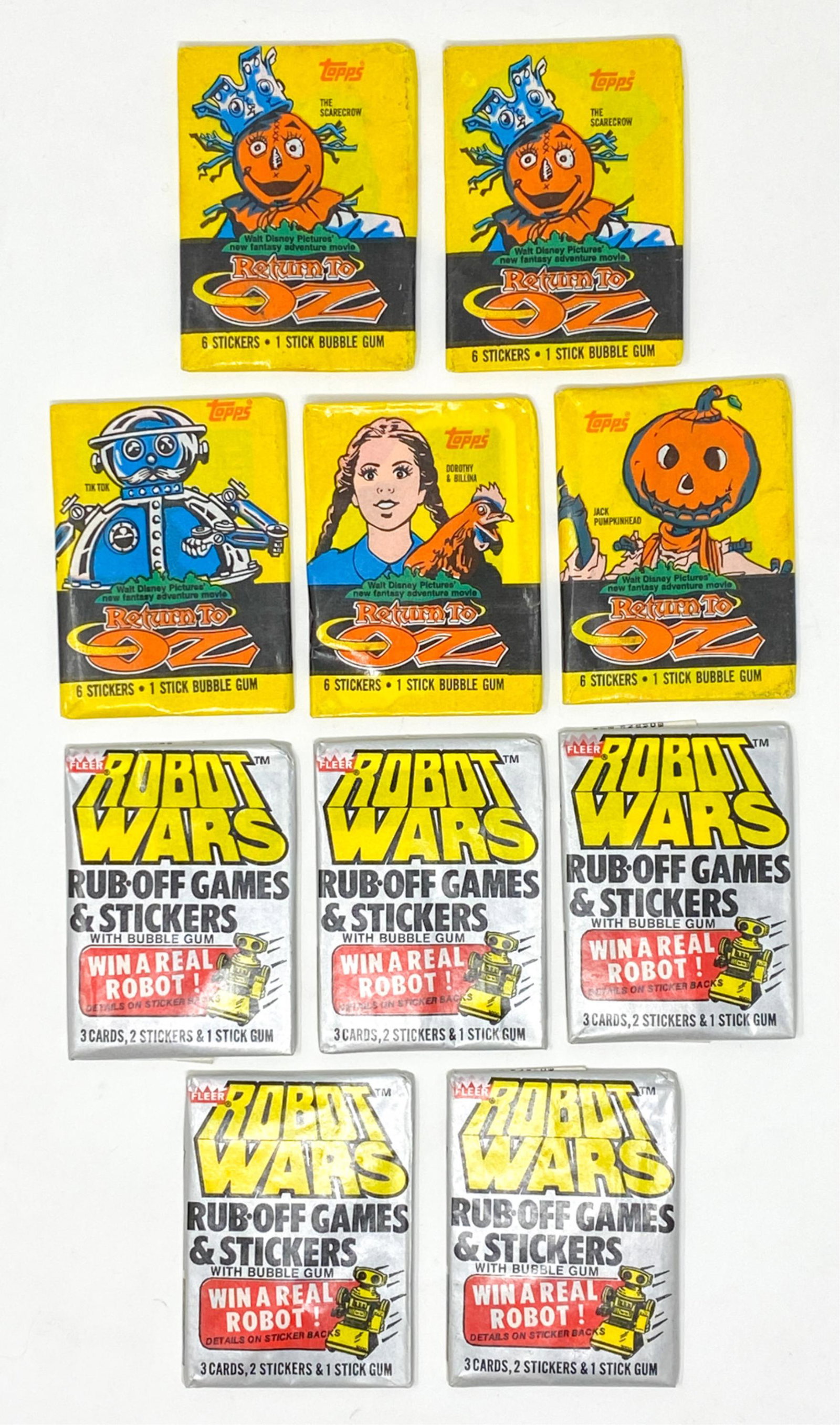 ROBOT WARS AND RETURN OF OZ TRADING CARDS: Including (5) Return to OZ trading card packs and (5) Robot Wars rub off games and stickers packs. Both from 1985 unopened packs. Dimensions: H 3.5" x W 2.75" Condition: Various stages of wear but goo