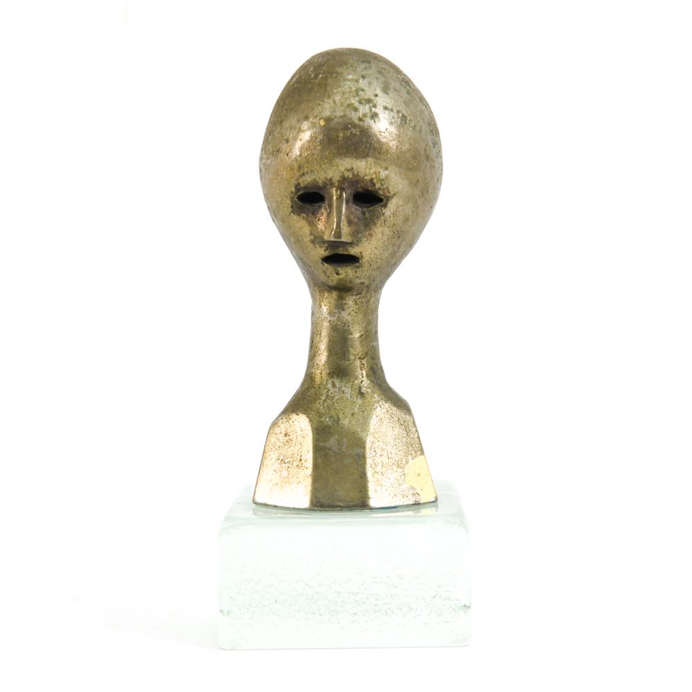 ANDRE MINAUX, FRENCH (1923-1986) METAL BUST C.1960: Mid-Century Modern casting of head with metallic bronze finish on solid glass pedestal. Signed Minaux with foundry mark and copyright on back of neck. Dimensions: H 12" x W 5" x D 5" Condition: Signs