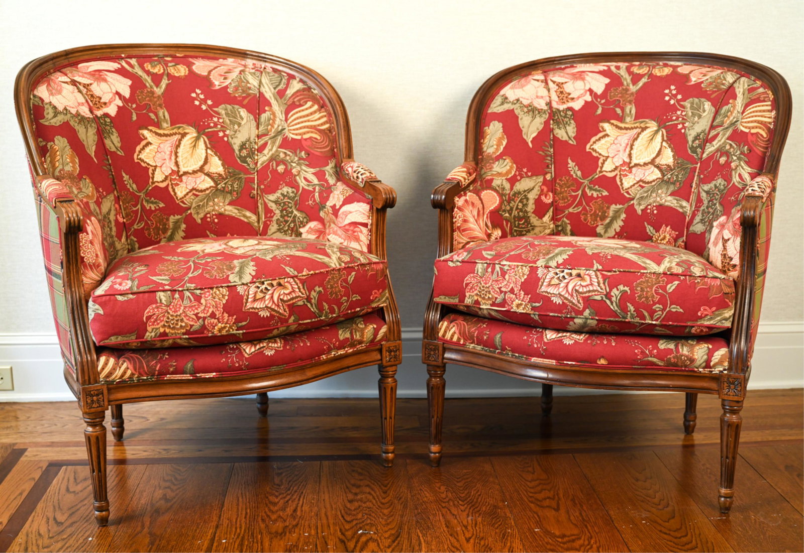 PAIR OF FRENCH STYLE UPHOLSTERED BERGERE CHAIRS: Fluted legs with rosette detail, piped upholstery. Dimensions: H 38" x W 30.25" x D 34" x SH 20" Condition: One slightly wobbly. Some sun fading to upholstery. Some nicks and dings to wood.