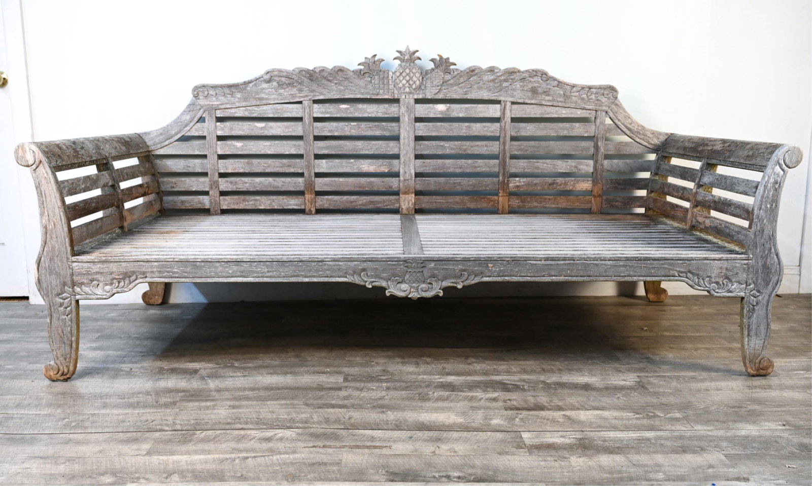 FRONTGATE CARVED TEAK PINEAPPLE OUTDOOR DAYBED: Carved pineapple motif, with Frontgate label on back. Dimensions: H 41.75" x W 89.75" x D 40" x SH 15" Condition: Wear consistent with outdoor use including small chip to pineapple carving, chip where