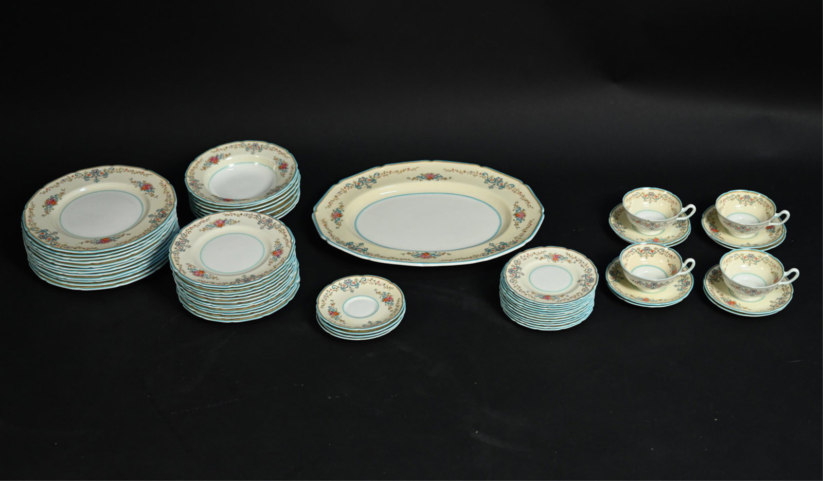 ROYAL DOULTON "THE PEMBROKE" BONE CHINA SERVICE: Marked underneath: Royal Doulton, The Pembroke. Including platter, four teacups, (12) larger saucers, (12) smaller saucers, (7) bowls, (12) smaller plates, (12) dinner plates. Dimensions: (Largest pla