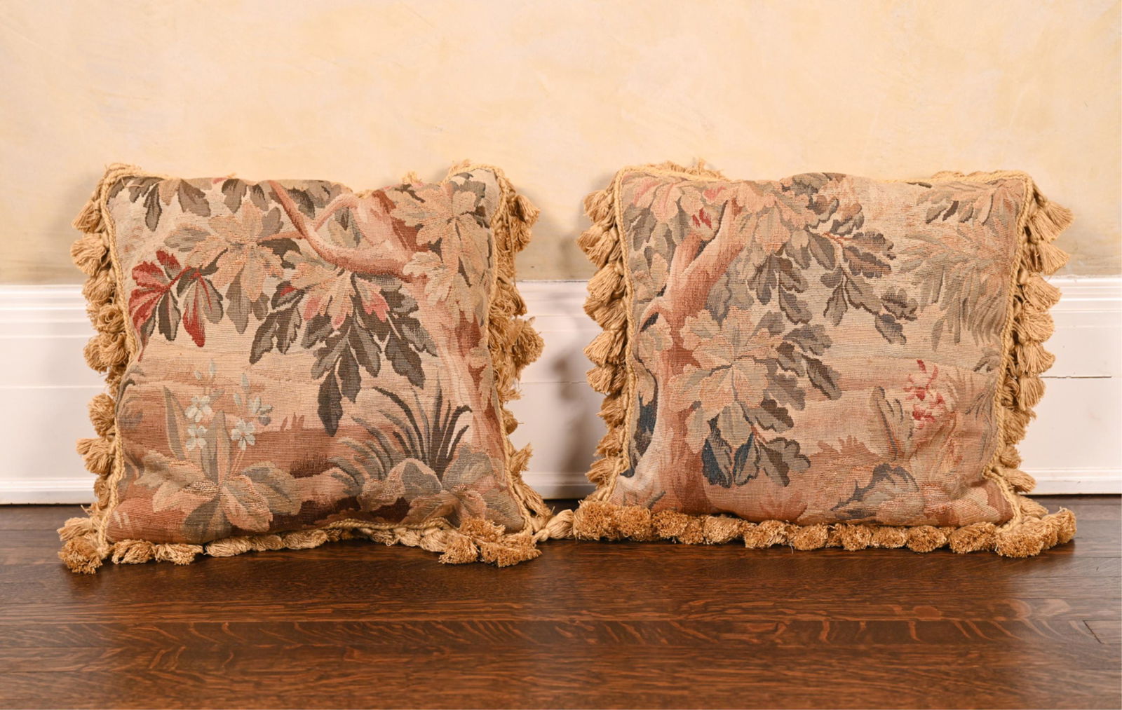 (2) AUBUSSON ANTIQUE TAPESTRY THROW PILLOWS: In beige toast with beige tassels. Originally priced at $1,695 each. Dimensions: L 17" x W 17" x D 4" Condition: Showing moderate wear, including spots of soiling, separation to one seam, (1) tassel n