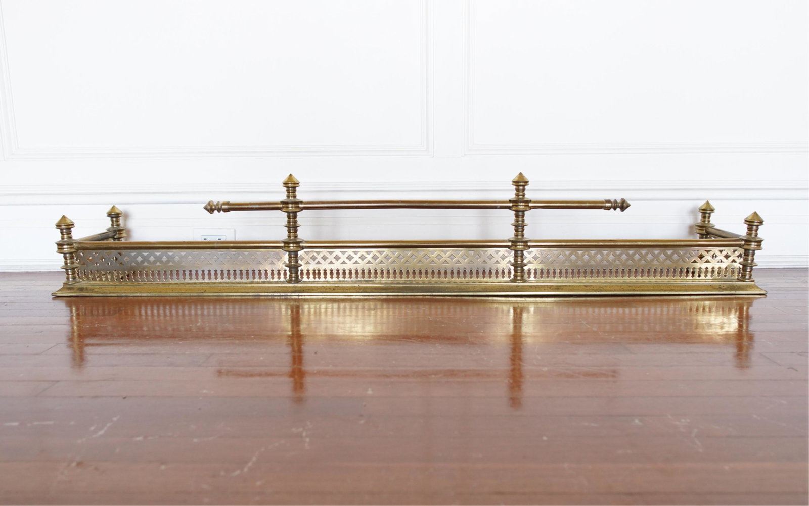 PIERCED BRASS FIRE FENDER: Dimensions: H 10.75" x W 62.5" x D 11.75" Condition: Tarnish, oxidation, and some dents. Signs of age and use.