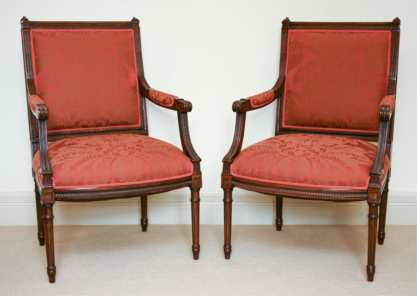 PAIR OF FRENCH LOUIS XVI STYLE ARMCHAIRS: With fluted, tapered legs and carved, beaded frames. Dimensions: H 38.25" x W 24.5" x D 20" x D 18" Condition: Few nicks and dings to edges, some rubs.