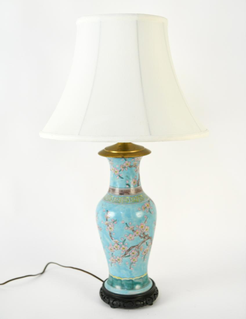 ANTIQUE CHINESE TURQUOISE PORCELAIN VASE, AS LAMP: Antique Chinese turquoise porcelain vase with cherry blossom motif, mounted as an electric lamp on a carved wooden base. Included with a white raw silk shade. Dimensions: (Without shade, to finial) H 