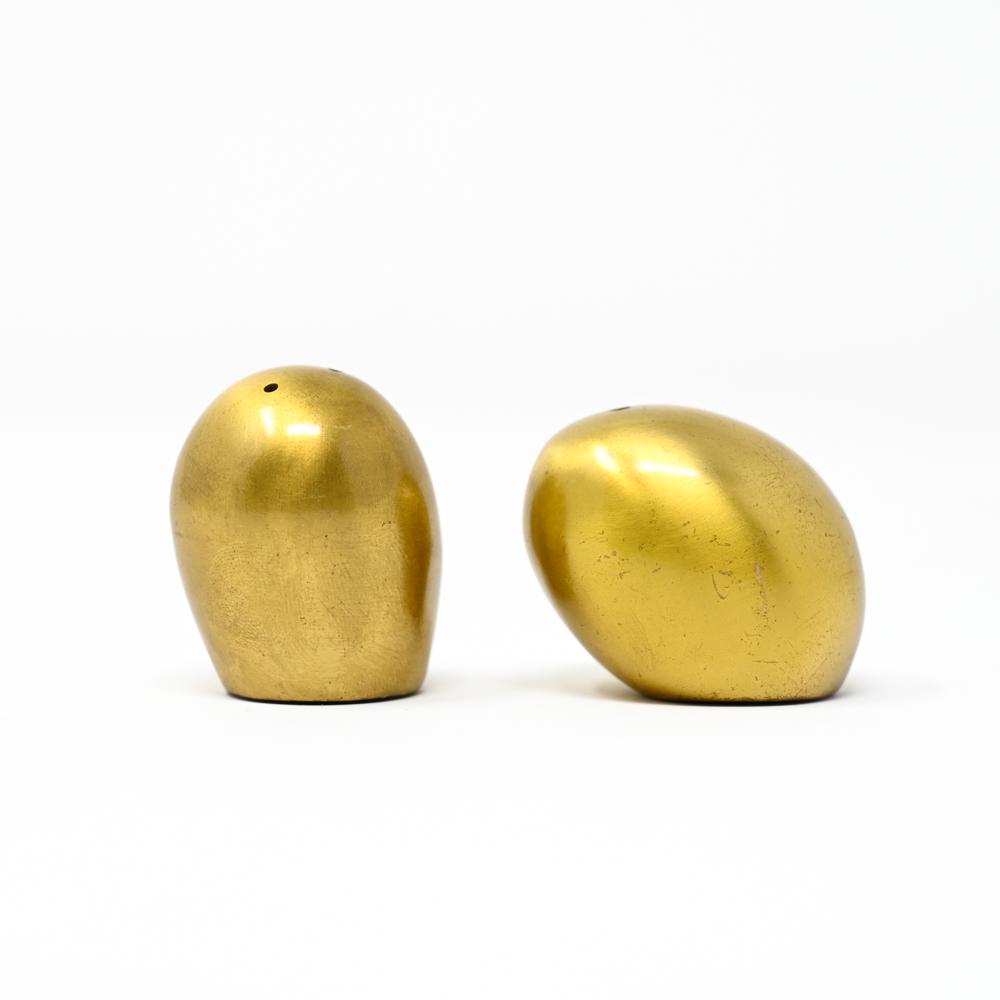 CAST BRASS OFFSET EGG SALT & PEPPER: Pair cast brass egg shape salt and pepper. Simple modernist design with a brushed brass finish. Apparently unmarked. Dimensions: (Tallest) H 1.75" x W 1.25" x D 1.25" Condition: Minor marks and scratc