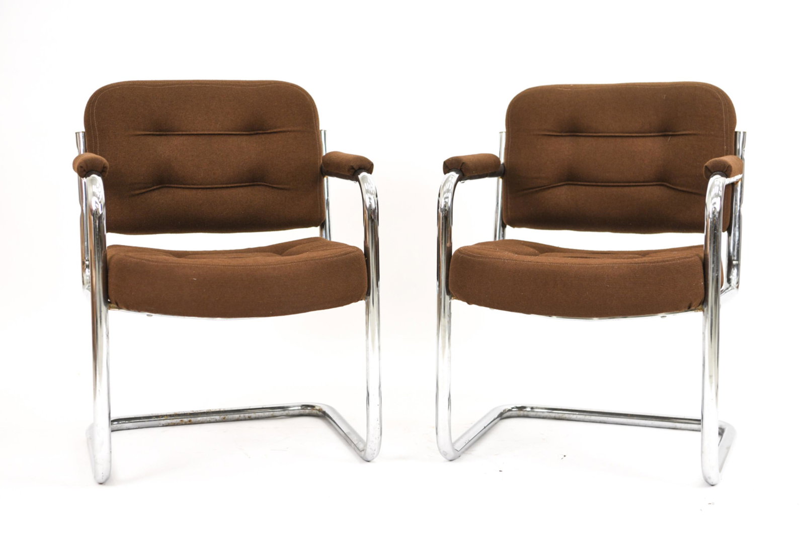 PAIR OF MID-CENTURY TUBULAR STEEL ARMCHAIRS: Well-cushioned, with brown upholstery. Made in Canada, label underneath. Dimensions: H 31" x W 23" x D 24" x SH 18" Condition: Some spots of corrosion and rust. Cushioning firm.