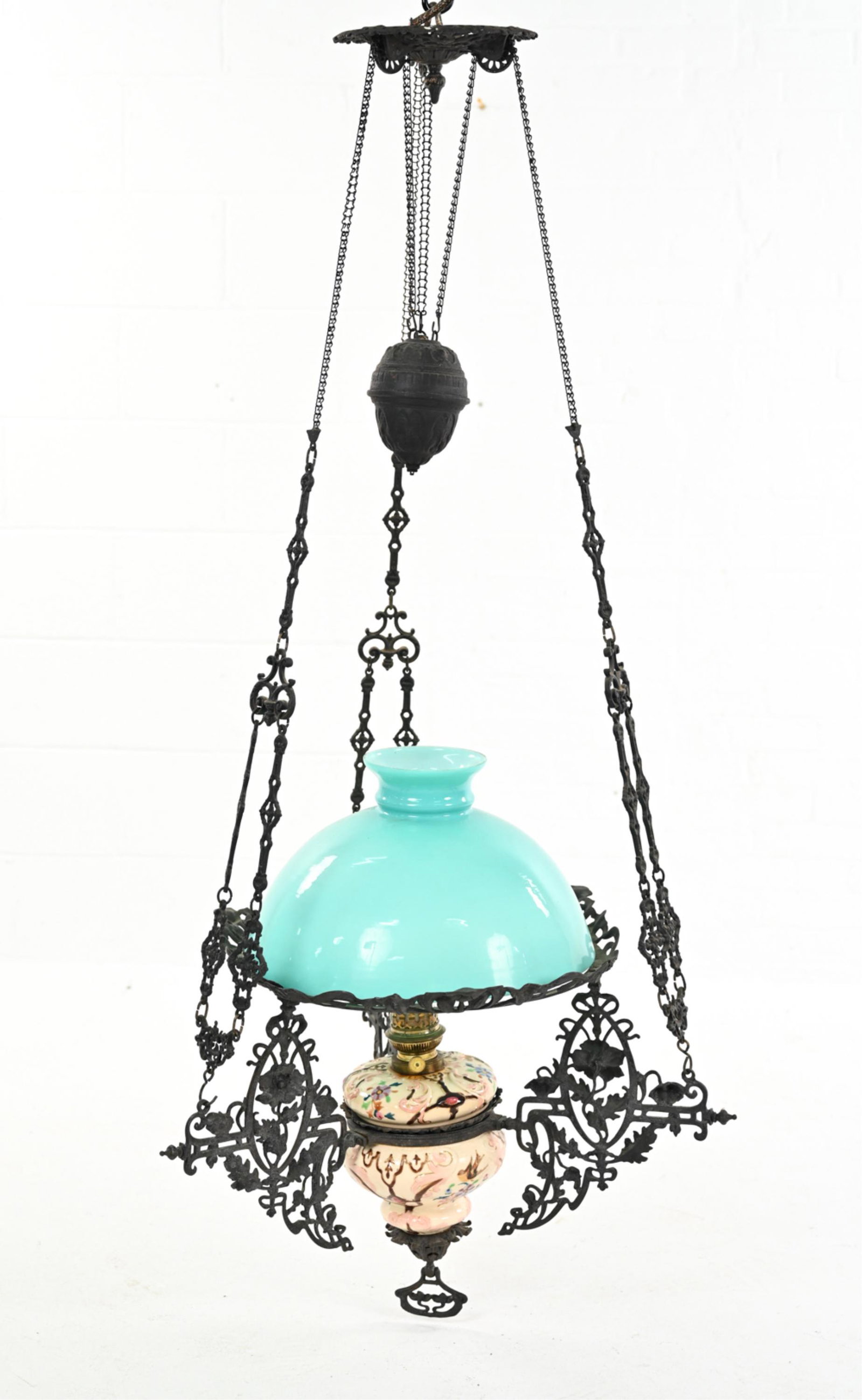 HANGING COUNTERWEIGHT PENDANT OIL LAMP: With wrought iron supports. Appears to be a Capodimonte base and oil lamp, not converted. Late 1800's. Currently has an aqua shade, not original. Dimensions: (Overall) H 58" x Dia. 26" Condition: Some