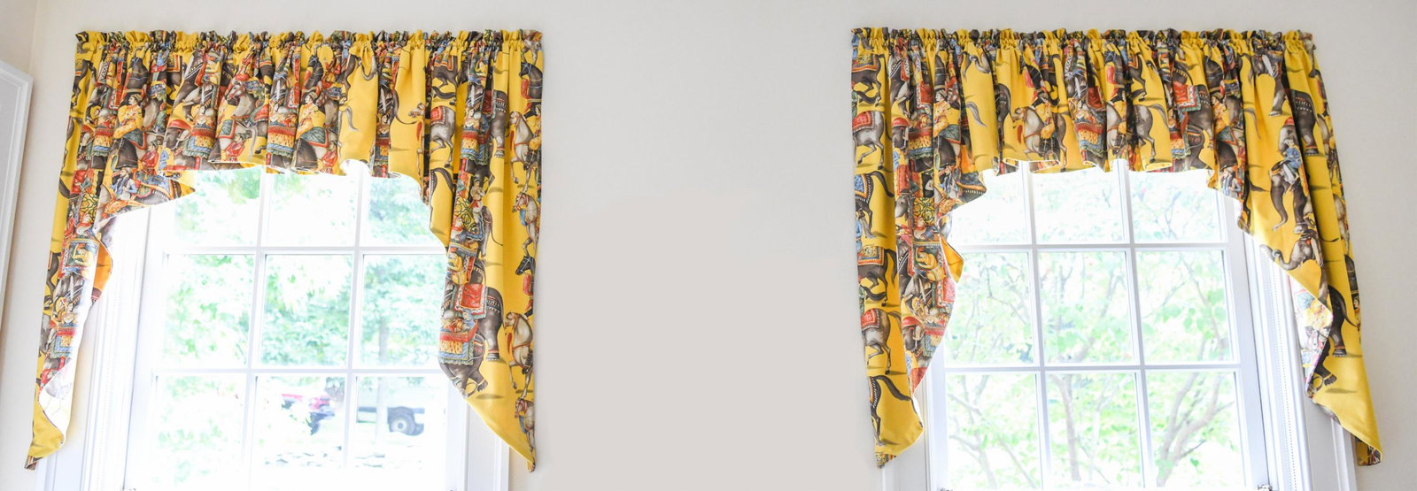 PAIR OF CUSTOM INDIAN-THEMED VALENCES: Pair of custom valences in Indian-themed fabric with elephants and horses on yellow ground. Dimensions: (As shown) H 40" x W 44" Condition: No issues to note.
