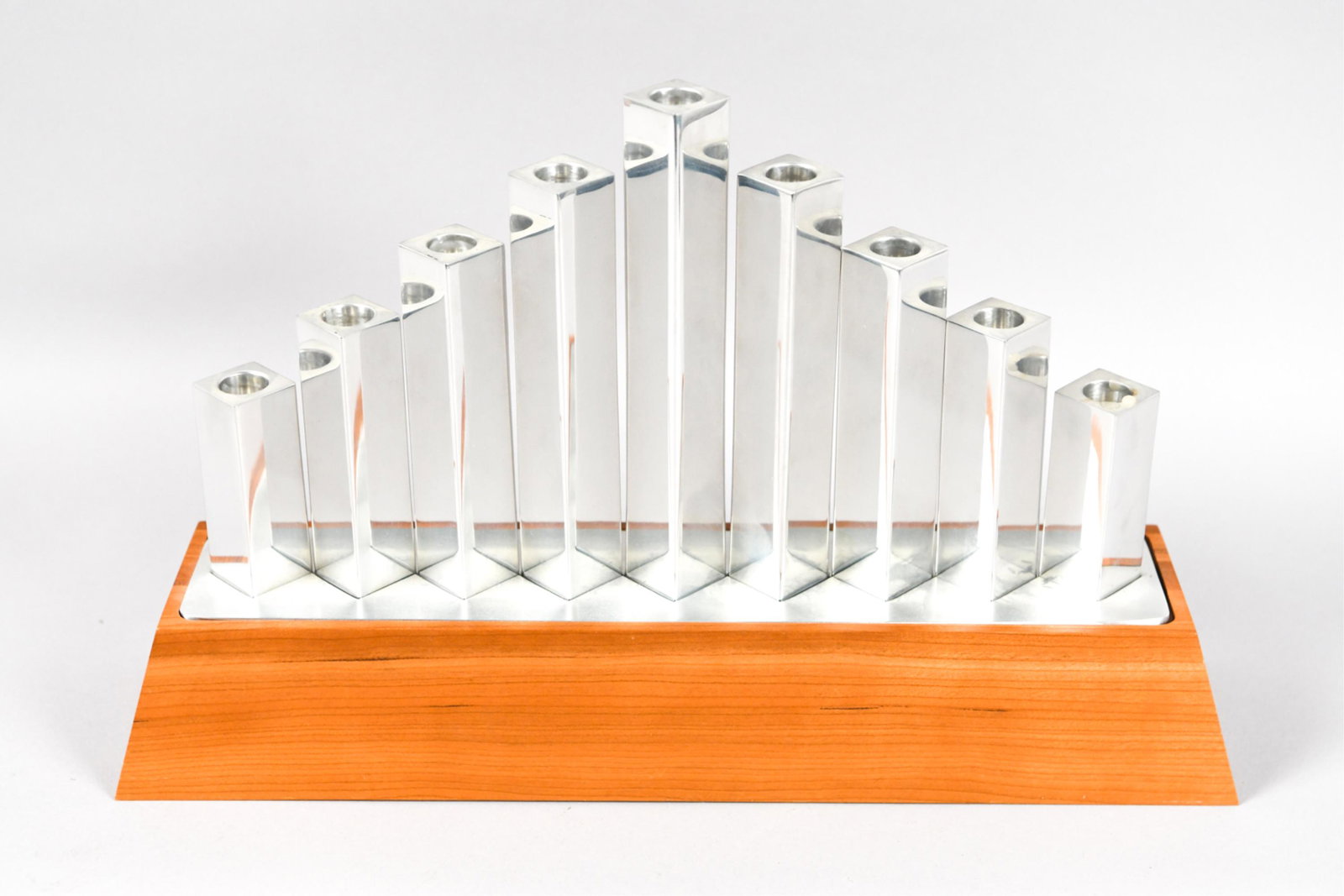 NAMBE STUDIO WOOD & ALUMINUM MENORAH: Cherry wood and polished aluminum. Dimensions: H 9.5 x W 15" x D 3.75" Condition: Surface scratches.