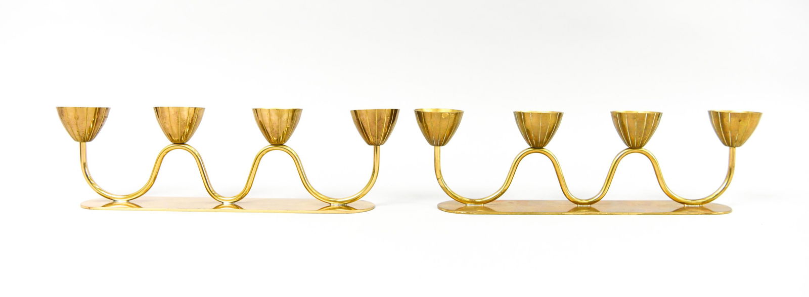 (2) GUNNAR ANDER FOR YSTAD CANDELABRAS: (2) Swedish mid-century brass flower-form 4-light candelabras. Designed by Gunnar Ander for Ystad-Metall, c. 1960's. Marked underneath. Dimensions: H 3" x W 10.5" x D 2" Condition: Tarnish, some verdi