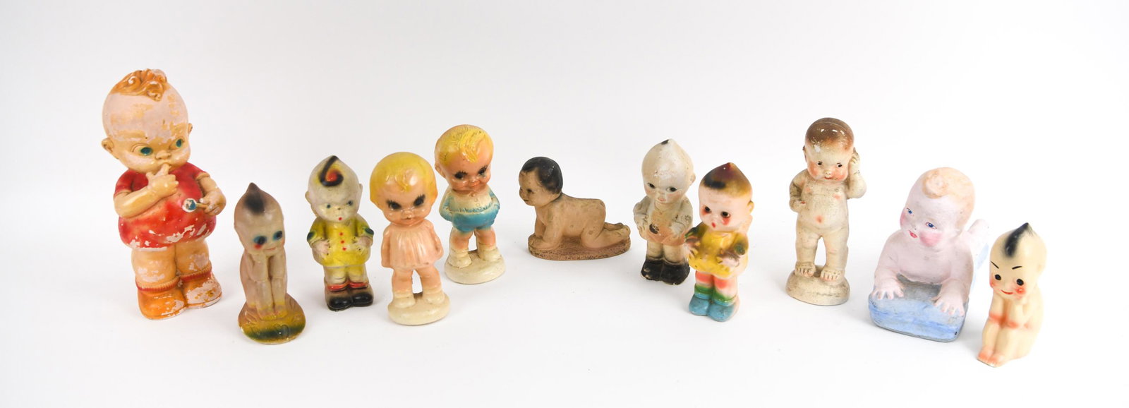 (11) CARNIVAL CHALKWARE BABIES: Including (11) carnival chalk ware babies with various poses and stages of painting. Dimensions: (Largest) H 9" x W 11" x D 5" Condition: Showing moderate wear consistent with age and use, including s