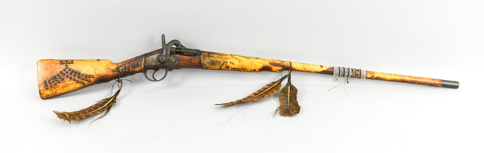 ANTIQUE NATIVE AMERICAN HIDE-WRAPPED SCOUT SHOTGUN: Rare Native American adorned rifle. Decorated with Native American symbols in brass tacks and animal hide barrel and stock covers, accented with glass seed beads, horse hairs, and turkey feathers. Mar
