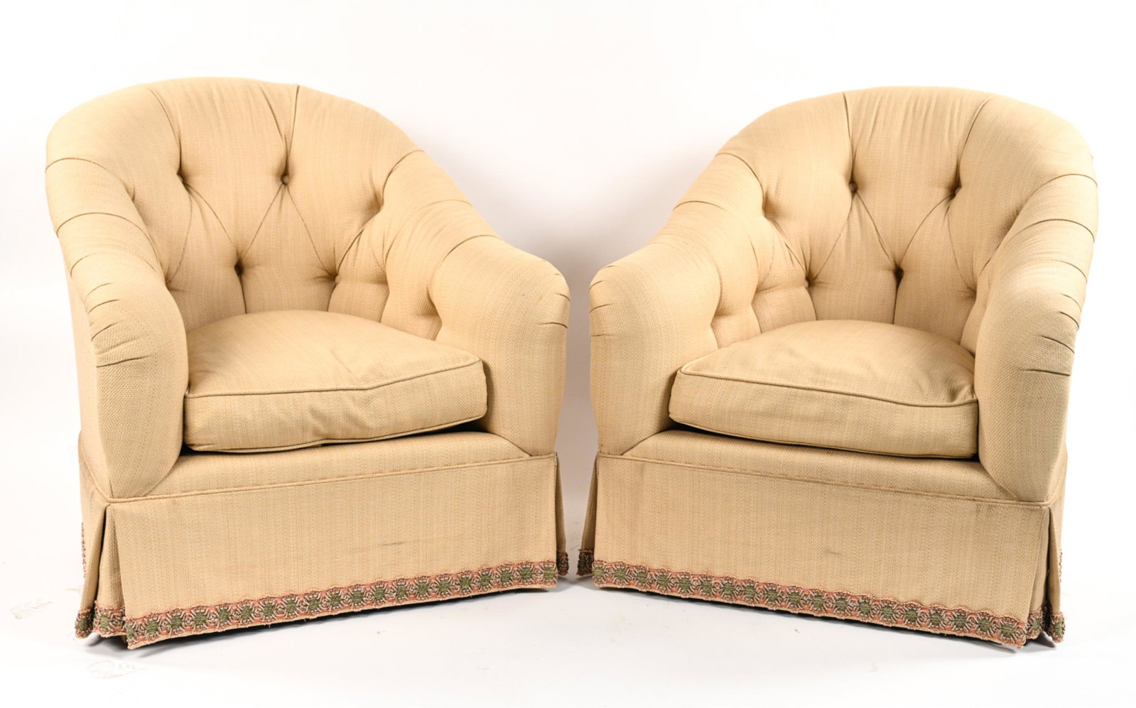 PAIR OF BUTTON TUFTED BARREL CHAIRS: Traditional tufted and skirted barrel chair Dimensions: H 34" x W 33" x D 30", SH: 17" Condition: Upholstery appears to be somewhat recent. Soiling around the piping along the upper portion of the ski