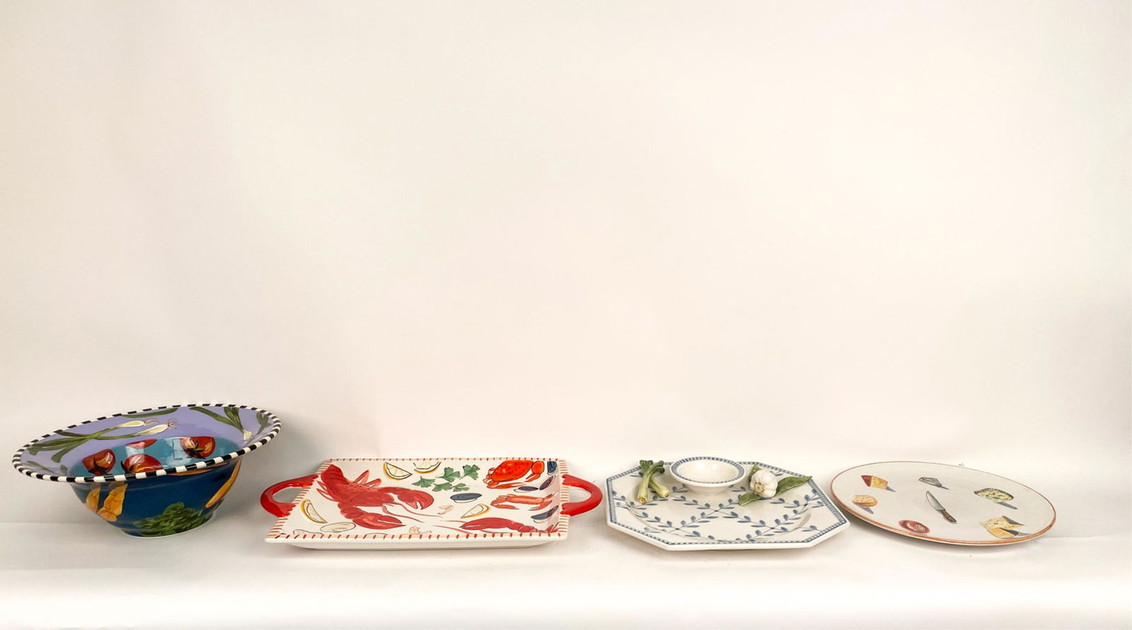 GROUPING OF HAND-PAINTED CERAMIC SERVEWARE: Including: large Droll Designs centerpiece salad bowl; cheese platter marked Italy and numbered 216/296; The Mane Lion vegetable and dip serving platter; and Mesa International lobster serving tray. D