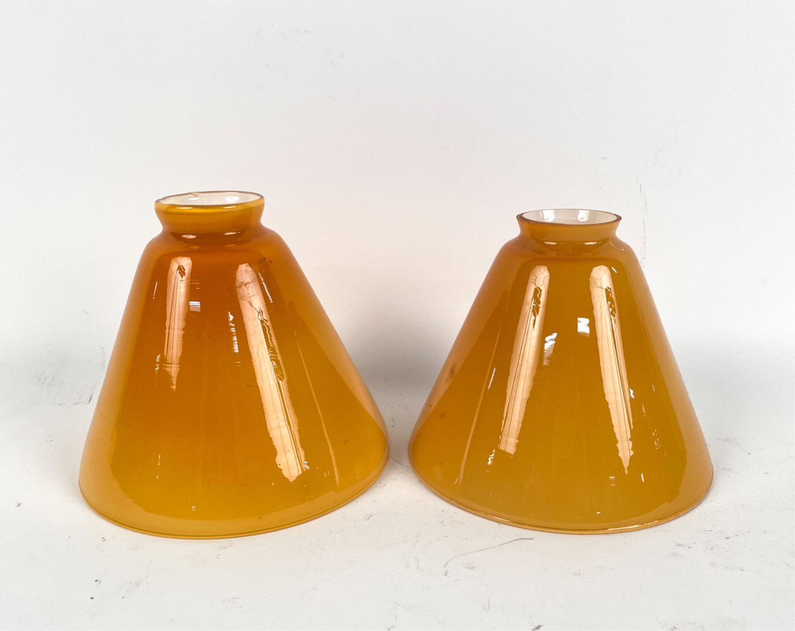 PAIR OF YELLOW CASED GLASS SHADES: Dimensions: (overall shade) H 5.5" x W 7" x D 7", (small end opening) Dia. 2" Condition: Very minor marks and rubs. Wear consistent with age and use.