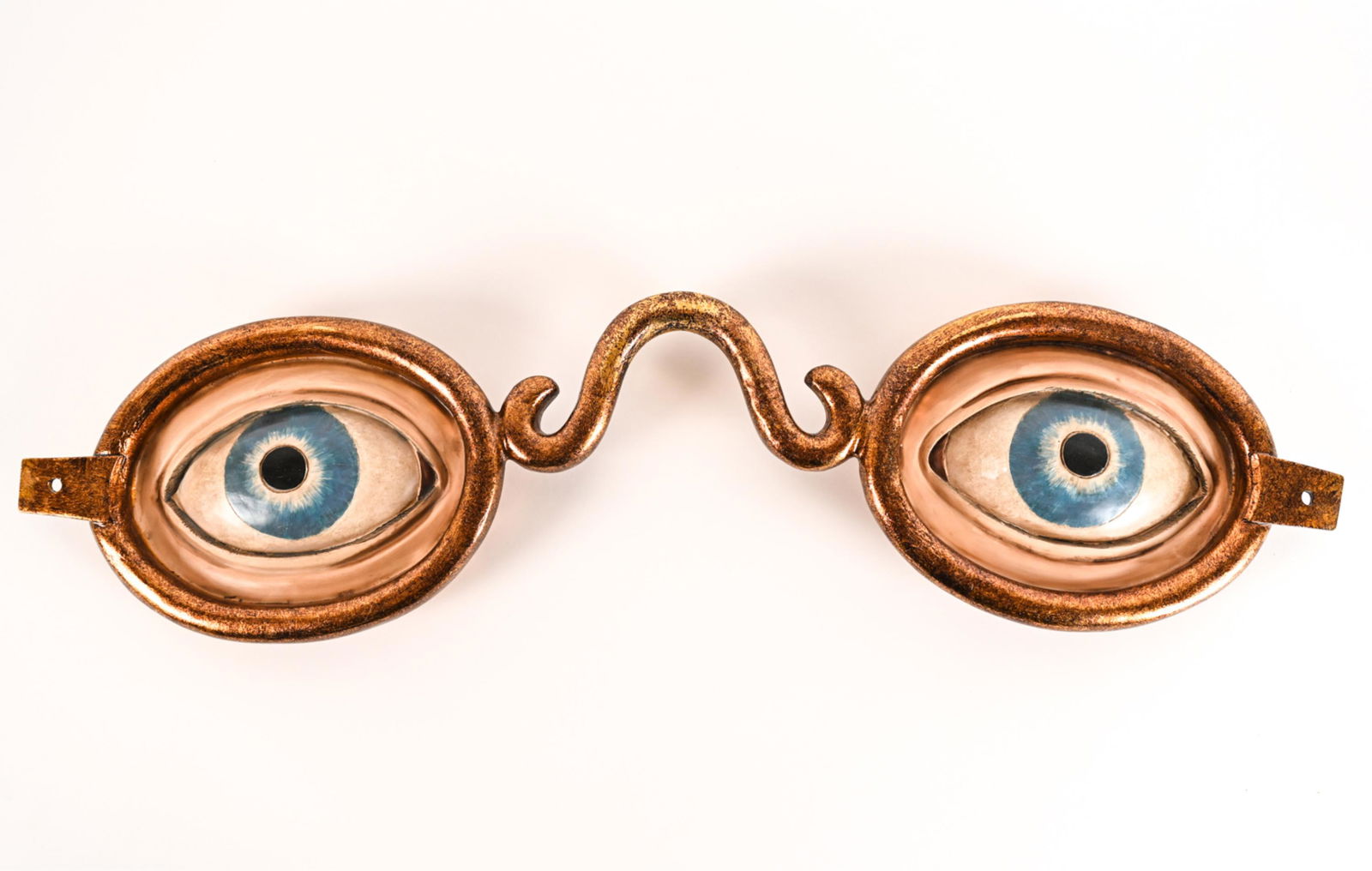 CONTEMPORARY DECORATIVE EYEGLASSES WALL HANGING: Marked PB 2080 verso. Depicting eyeglasses with blue eyes. Dimensions: H 9" x W 35.5" x D 2.5" Condition: Minor surface wear.