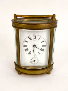 ANTIQUE TIFFANY & CO CARRIAGE CLOCK: Tiffany & Co. oval brass carriage clock with beveled glass. Marked made in France, signed and numbered to back of movement. Dimensions: H 4.25" x W 3" x D 2.25" Condition: Rich patina and surface wear