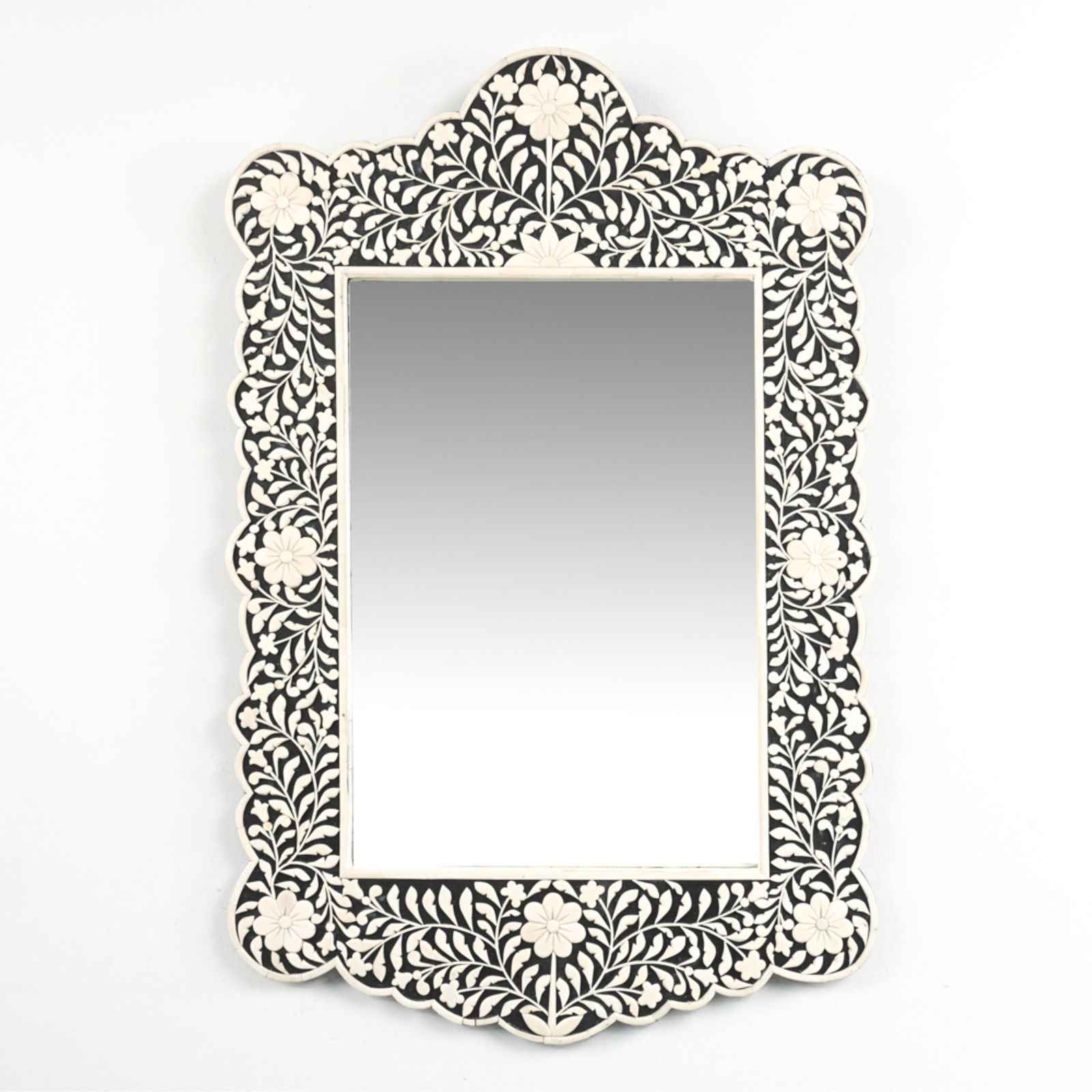 CONTEMPORARY INDIAN CARVED BONE WALL MIRROR: Ebonized wood frame with carved bone inlay, Made in India label on back. Dimensions: H 36.25" x W 23.5" Condition: Bone inlay with a few cracks, nicks and small surface losses. A few scuffs and rubs t