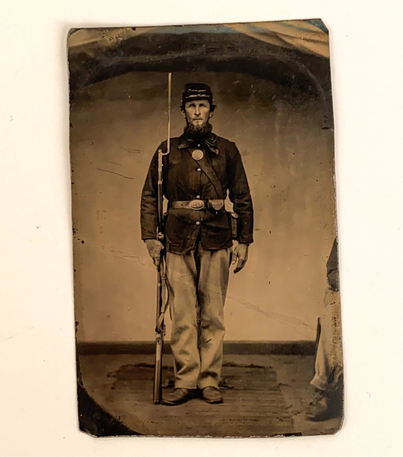 1/6 PLATE TINTYPE CIVIL WAR SOLDIER W/ RIFLE: Standing full length with bayonet affixed. Dimensions: H 4" x W 2.75" Condition: Light folds, damage at edges.