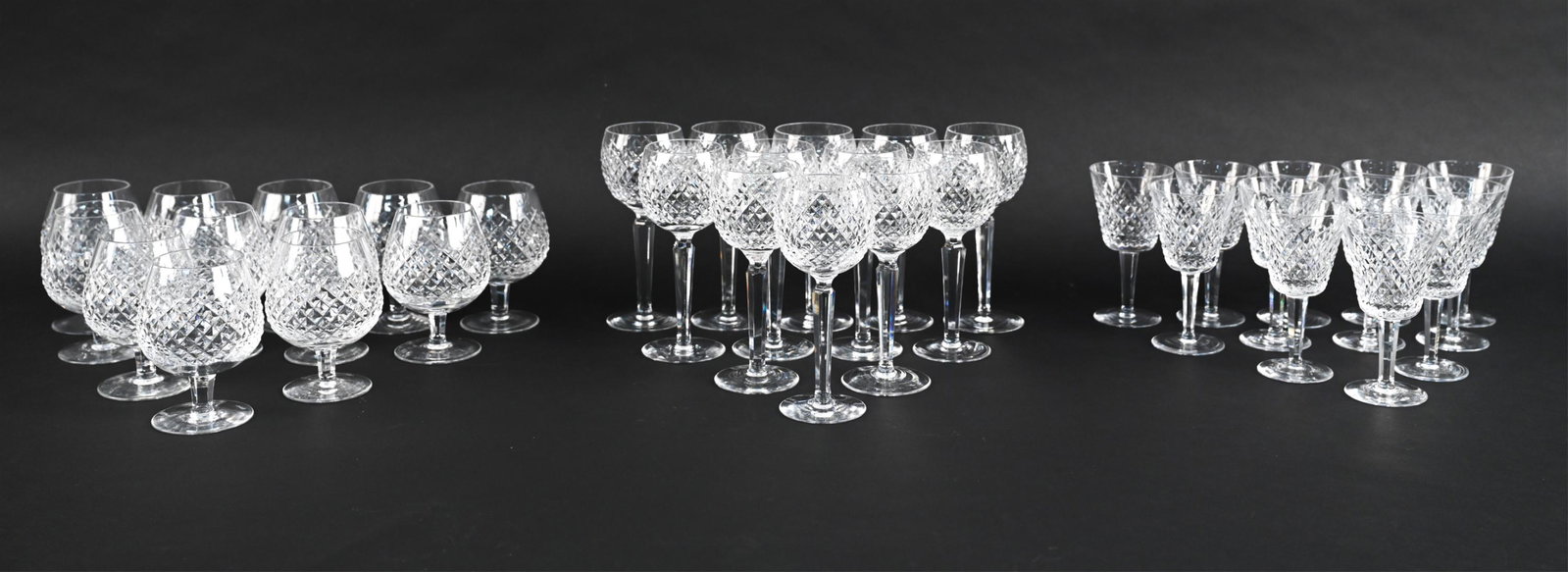WATERFORD CUT CRYSTAL GLASSES SERVICE FOR (12): Including (12) wine goblets, (12) port or white wine glasses, and (12) brandy snifters. All marked underneath. Dimensions: (Wine goblet) H 7.5" x Dia. 3" Condition: Minor use wear.