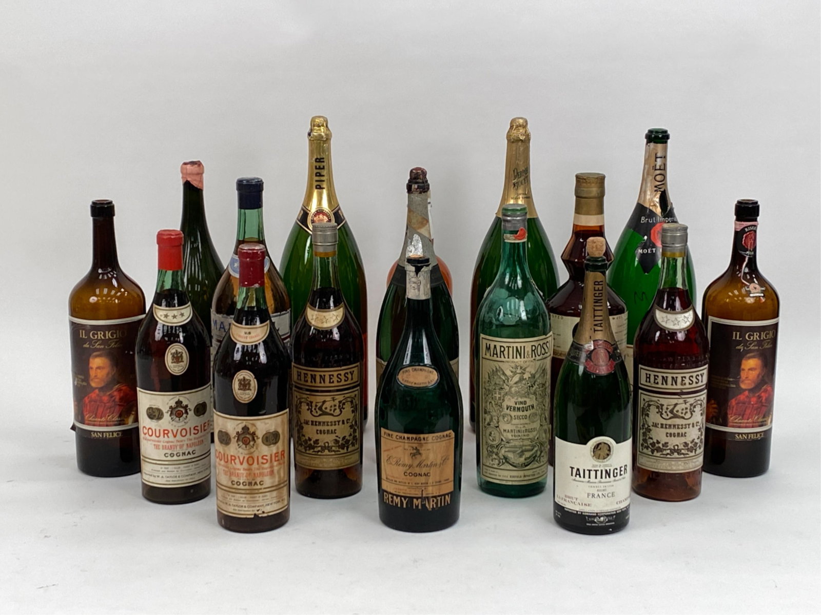 (17) VINTAGE OVERSIZED WINE BOTTLES: Decorative grouping of oversized wine and liquor bottles. Dimensions: (Tallest) H 26.5" x Dia. 8.5" Condition: All empty, some painted to appear full. Handling wear including some soiling and losses t