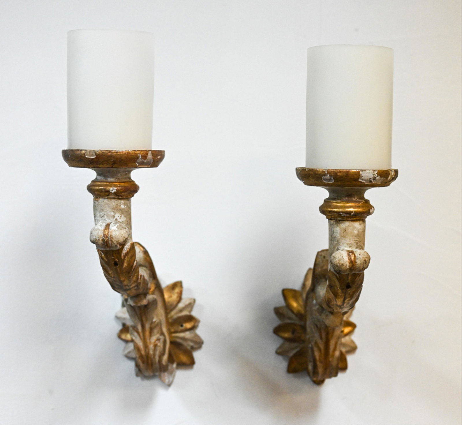 PAIR OF LOUIS XIV-STYLE CARVED GILTWOOD SCONCES: Substantial single-light sconces of carved wood, painted cream and partially gilded. With removable wax faux-candle hurricanes. Apparently unlabeled, contemporary. Dimensions: (With candle) H 16" x W 