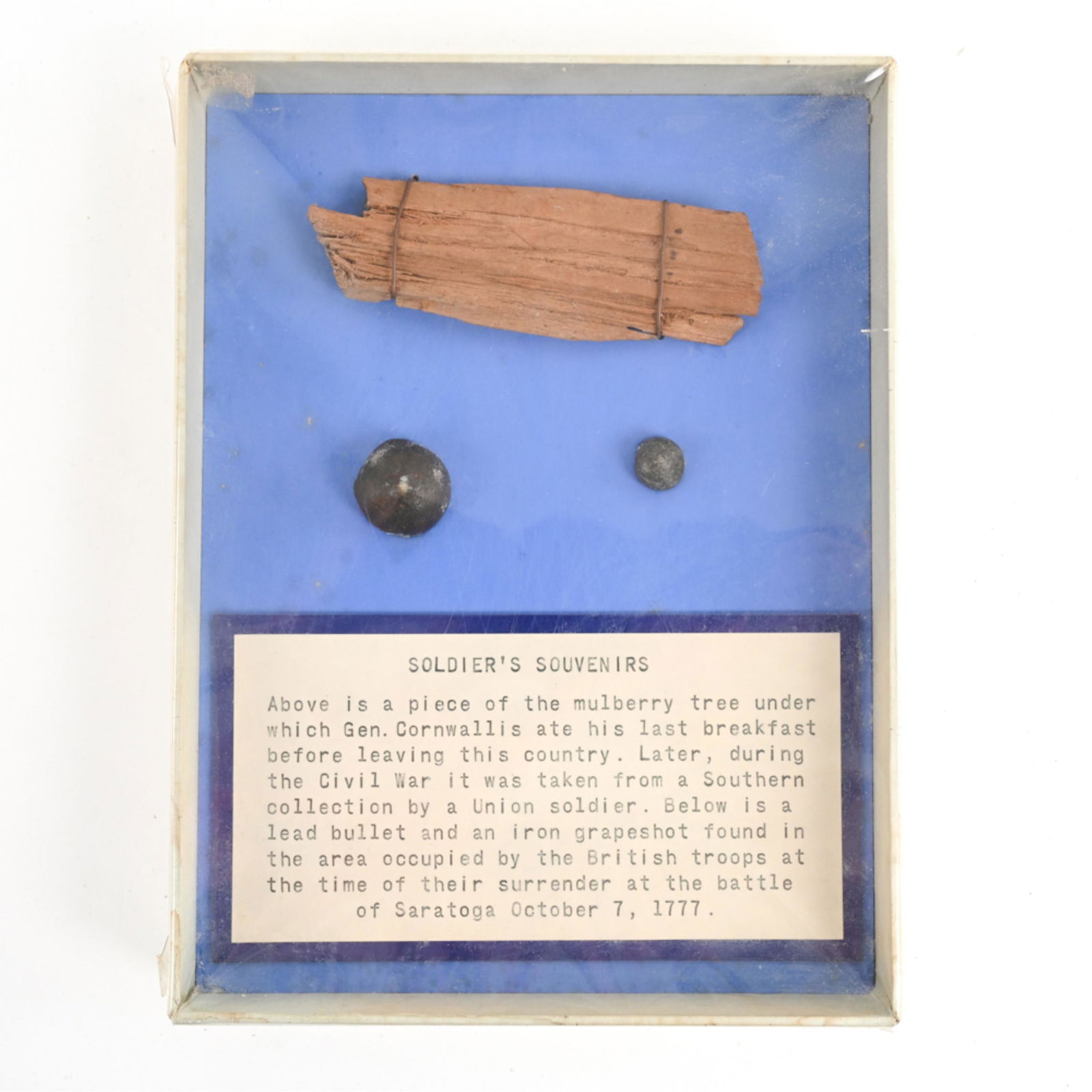 REVOLUTIONARY WAR "SOLDIER'S SOUVENIRS": All mounted in frame with description. Purportedly a piece of mulberry tree under which Gen. Cornwallis ate his last breakfast before leaving the country, lead bullet, and iron grapeshot from area occ