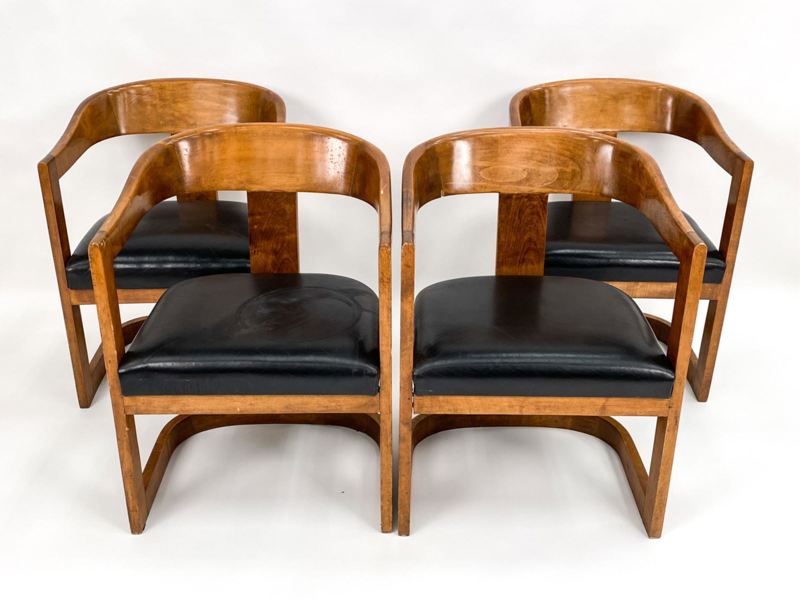 (4) MID-CENTURY ART DECO-STYLE BARREL CHAIRS: Quality wood frames with black leatherette seats. No labels. Dimensions: H 30.5" x W 21.75" x D 21.5" x SH 18.5" Condition: Some looseness to joints, cracks, and loss to one seat back. Seats with some