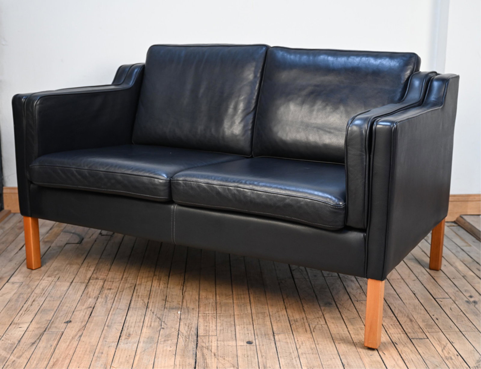 MID-CENTURY STOUBY LEATHER SETTEE: Dimensions: H 31" x W 56" x D 32" x SH 15" Condition: Showing very light wear consistent with age and use.