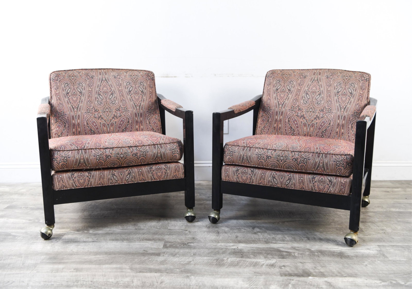 PAIR MID-CENTURY DIRECTIONAL LACQUER LOUNGE CHAIRS: Matched pair of chairs by Directional. Black lacquered wood with paisley upholstery. On casters. Dimensions: H 29" x W 25.75" x D 28" Condition: Few nicks and dings to edges. Fading to upholstery. Few