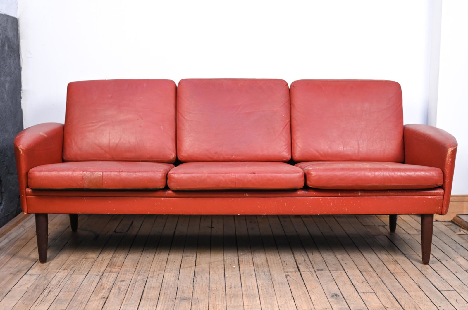 MANNER OF SVEND SKIPPER MID-CENTURY LEATHER SOFA: Dimensions: H 27" x W 71" x D 30" x SH 15.5" Condition: In need of reupholstering or restoration; leather stiff, with scuffs, spots of soiling, scratches, and small losses to corners. Cushions slightl