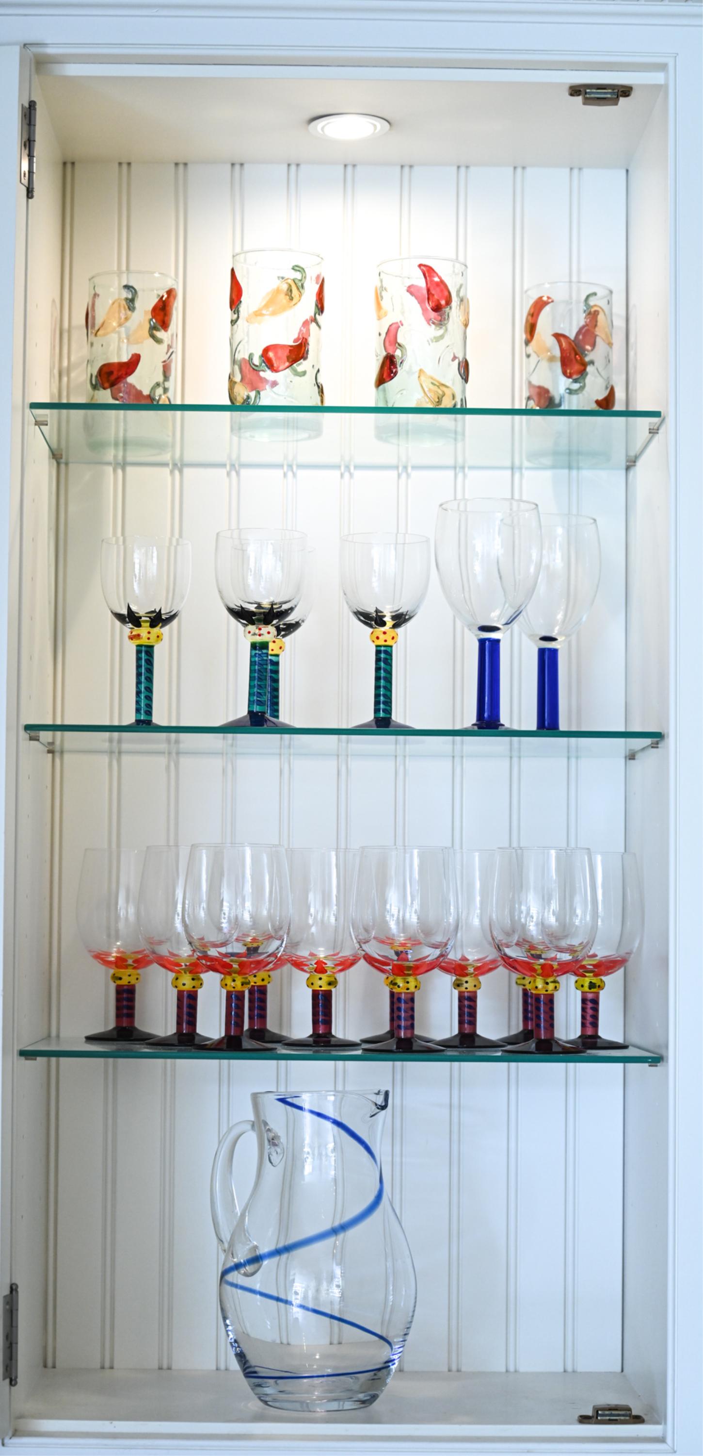 GROUPING OF ART GLASS BARWARE INCL. KOSTA BODA: Including: (4) pepper motif highball tumblers, (2) goblets with cobalt stems, (1) cobalt swirl pitcher, and (15) painted goblets by Kosta Boda (four blue/green wine goblets and eleven red/blue water g