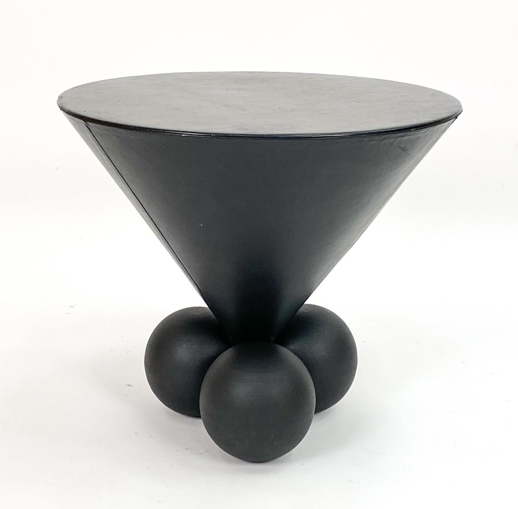 STANLEY JAY FRIEDMAN BRUETON BOCCI TABLE: Leather "Bocci" occasional table designed by Stanley Jay Friedman for Brueton. Apparently unmarked. Dimensions: H 21.75" x Dia. 24" Condition: Surface wear, scratches and indentations in leather consi