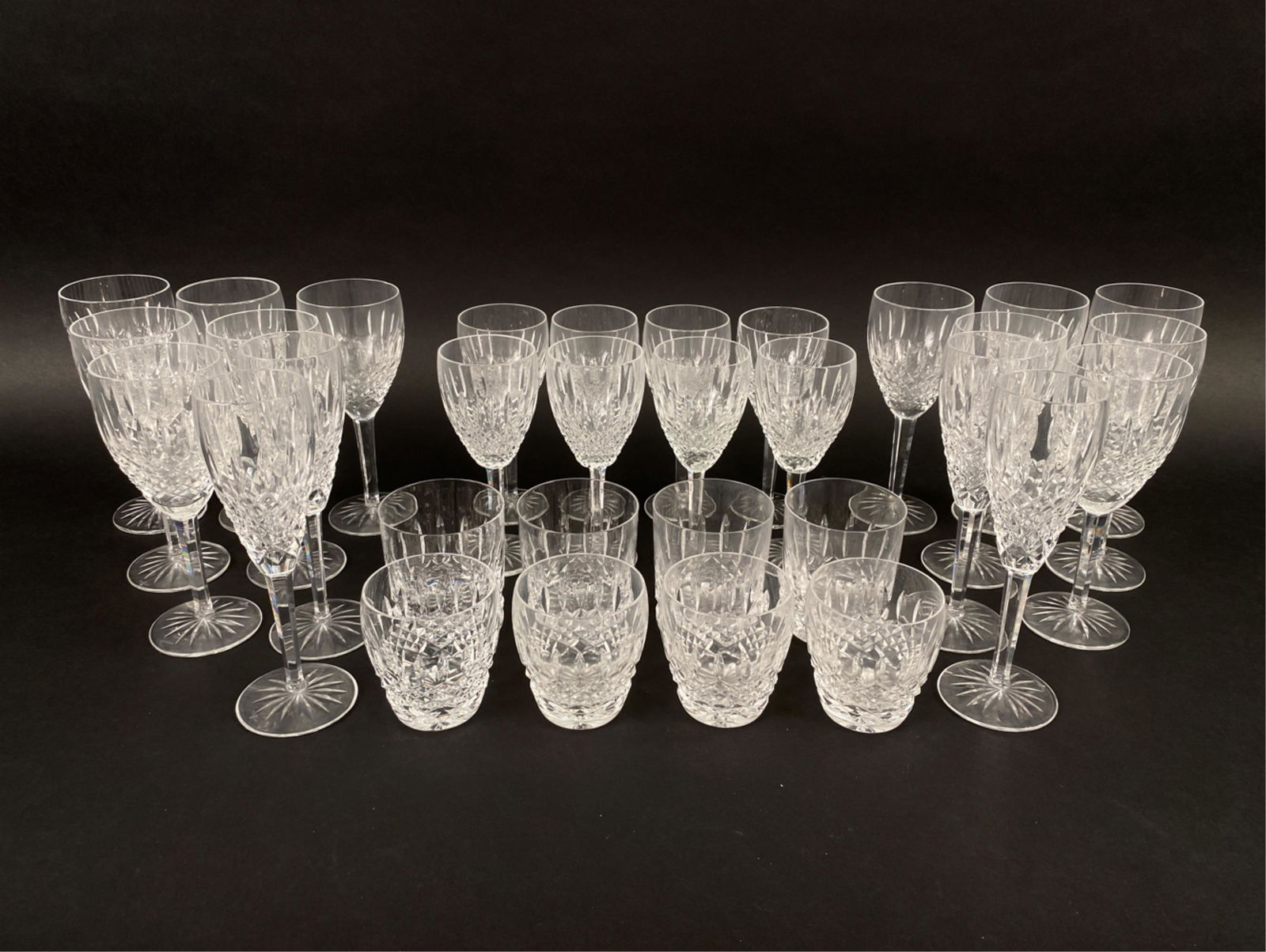 WATERFORD LISMORE CRYSTAL GLASSWARE SERVICE: Marked Waterford underneath. Including (4) lowball glasses, (4) water glasses, (8) white wine goblets, (4) champagne flutes, and (12) red wine goblets. Dimensions: (Largest) H 8" x Dia 3" Condition: O