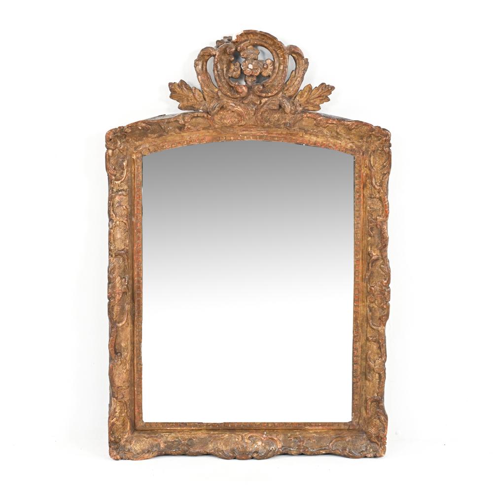 ANTIQUE FRENCH LOUIS XVI-STYLE GILTWOOD MIRROR: Carved giltwood and gesso mirror with floral crown motif, c. Early 19th Century - possibly older. Dimensions: H 38" x W 25" Condition: Rubbing and dullness to gilding; possible overpainting. Old repai