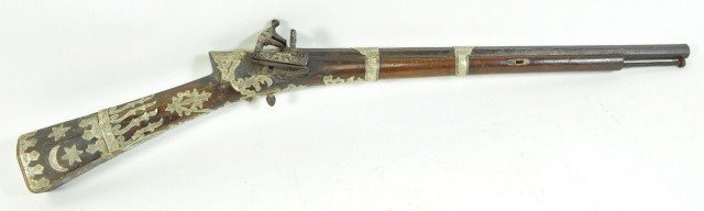 19TH C. OTTOMAN RIFLE: The wooden parts are mounted with silver and decorated with Islamic motifs. The gun is relatively small since it was designed specifically for shooting during horse riding.