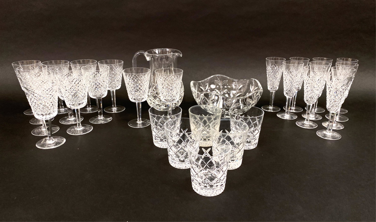 GROUPING OF CRYSTAL INCL. WATERFORD: Includes (10) Waterford champagne flutes, (12) Waterford wine goblets, (6) Waterford highball glasses, Tiffany bowl, and a Waterford pitcher. Dimensions: (Pitcher) H 8.5" x W 7.5" x D 5.5" Condition: 
