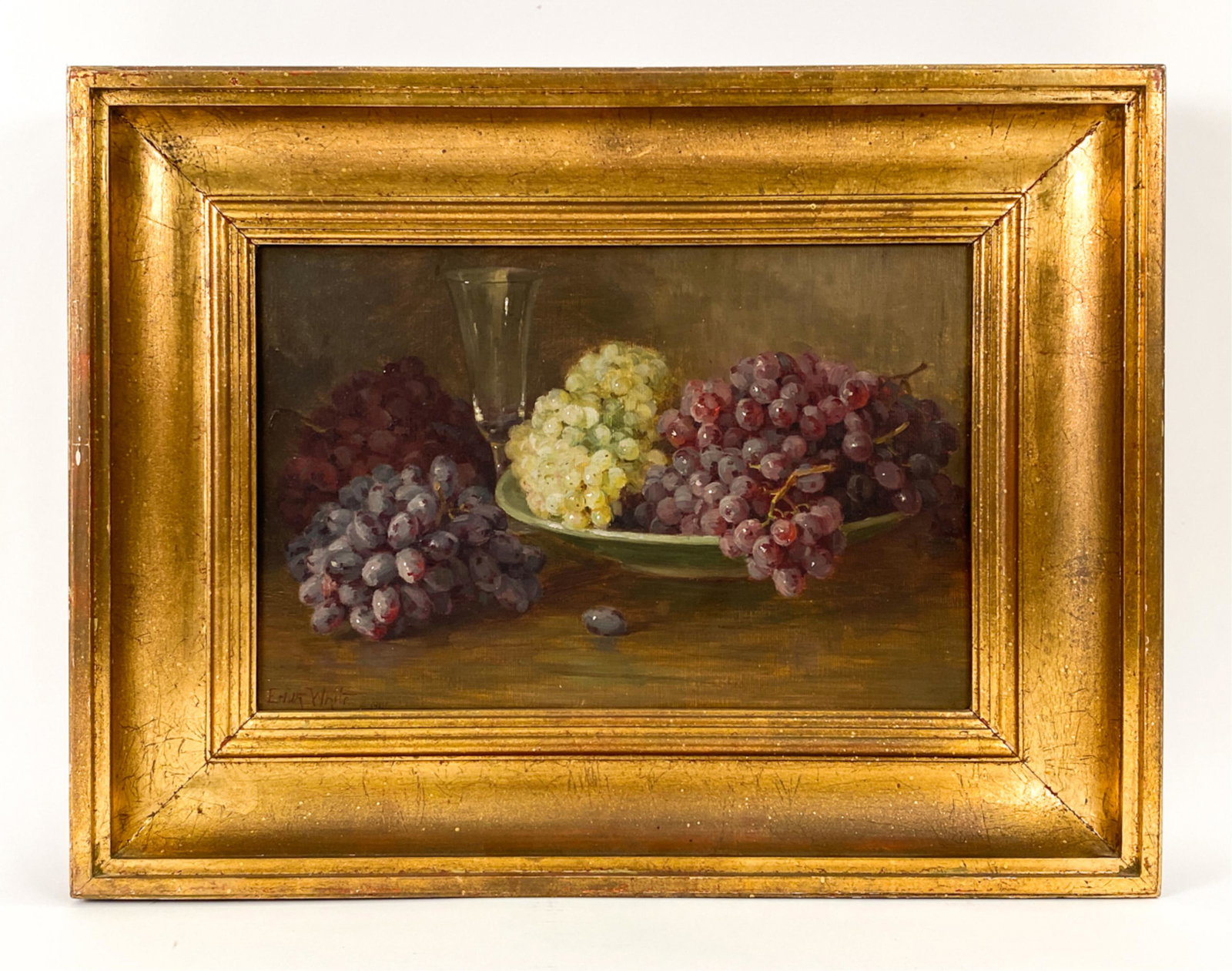 EDITH WHITE, CALIFORNIA (1855-1946) STILL LIFE: Still life of grapes with wine glass. Oil on canvas. Signed lower left. Dimensions: (Frame) H 19.5" x W 25.5", (Painting) H 12" x W 18" Condition: Small patch hole lower right corner. Unvarnished surf