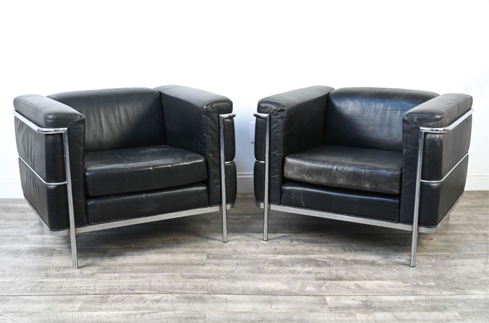 PAIR OF JACK CARTWRIGHT LEATHER CLUB CHAIRS: Leather and chrome cube-style lounge chairs inspired by Le Corbusier; with original labels underneath, c. 1988. Dimensions: H 26.5" x W 34" x D 31" x SH 16" Condition: Leather with natural patina and